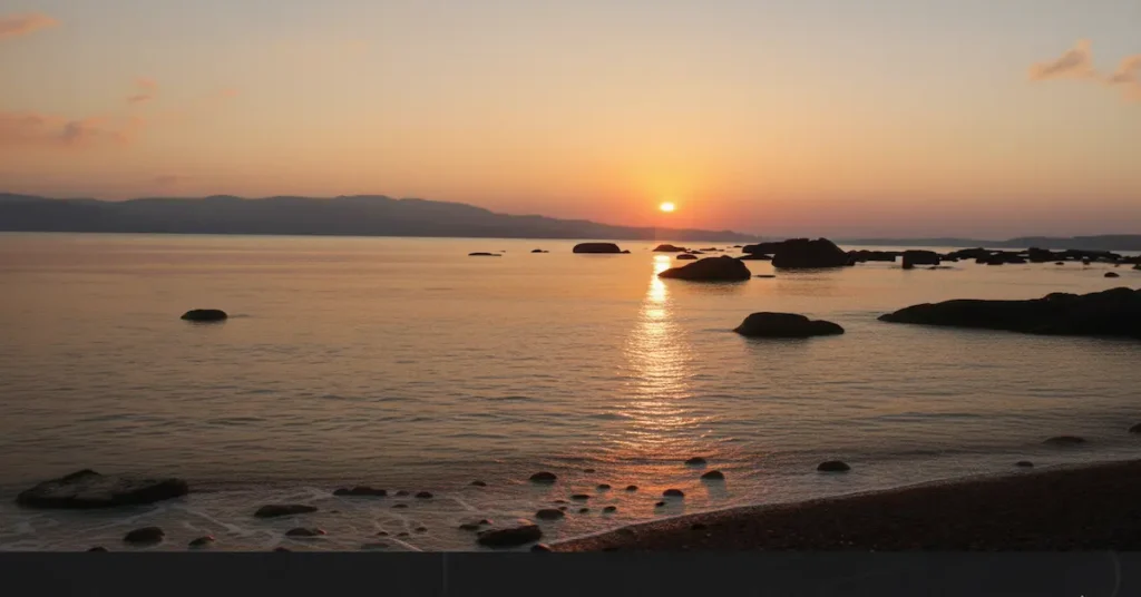 Sunset view at Chidiya Tapu Beach in Andaman with golden sunlight reflecting on calm sea and scattered rocks along the shoreline.